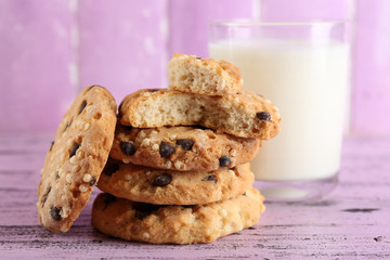 Tasty cookies and glass of milk on color wooden background