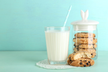 Tasty cookies and glass of milk on color wooden background