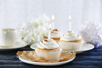 Delicious birthday cupcakes on table on light background