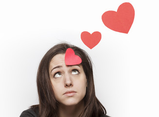 Sad girl looking at red paper hearts