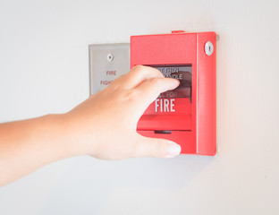 The hand  is pulling fire alarm on the wall