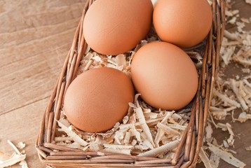 Egg on sawdust with old basket over on wooden background