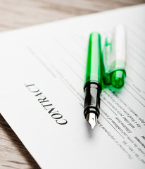 Pen and contract papers on wooden desk
