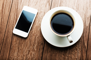 Fototapeta na wymiar smart phone and coffee cup on wooden background.