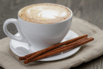 cup of cappuccino with cinnamon sticks