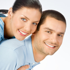 Cheerful amorous young couple, on grey