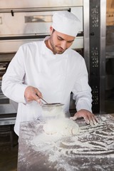 Focused baker sieving flour on the dough