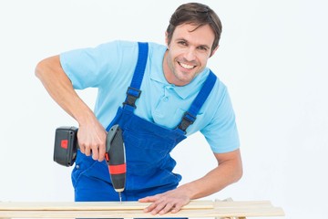 Carpenter using drill machine on wood