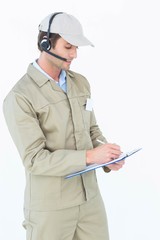 Delivery man using headphones while writing on clipboard