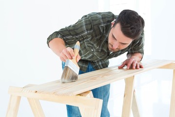 Worker using brush on wooden plank