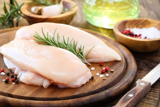 Raw chicken breast with fresh rosemary sprig and spices