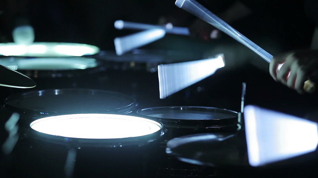 Playing glowing drums with neon drumsticks. Close-up