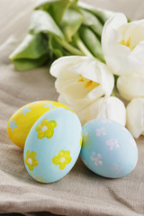 Fototapeta na wymiar handpainted easter eggs and white tulips on wood table