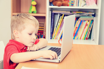 little boy working on laptop at home