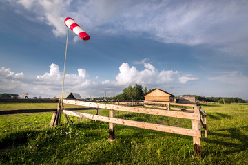 Red vane on the background of the village hangar in the summer