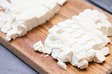 Closeup of paneer cut into pieces on cutting board