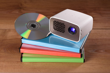 Mini Beamer mit DVD und DVD-HŸllen auf Holztisch