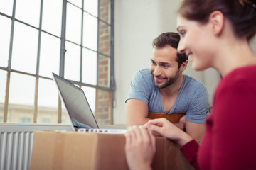 paar schaut auf laptop während des umzugs