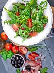 Sliced prosciutto with salad and olive