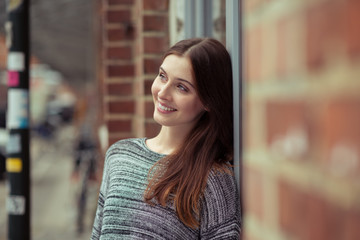 glückliche frau lehnt draußen an einer hauswand