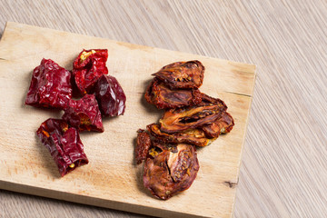 Spicy dried peppers and tomatoes on a wooden kitchen board