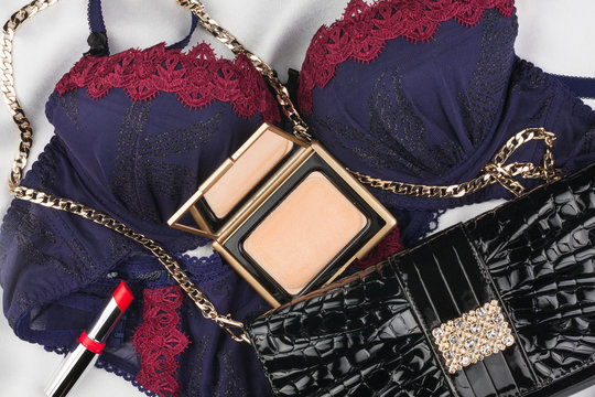 Beautiful clothes and cosmetics lying on white satin
