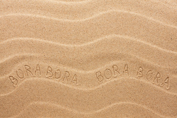 Bora Bora inscription on the wavy sand