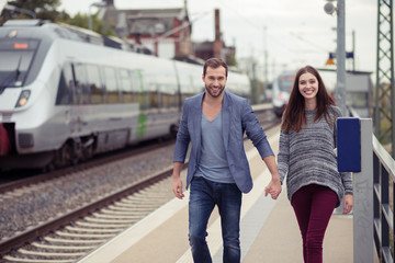 lächelndes paar geht den bahnsteig entlang