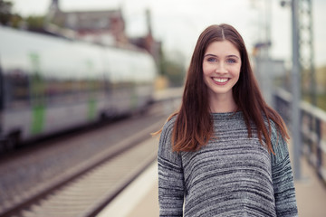Fototapeta premium lächelnde junge frau am bahnsteig