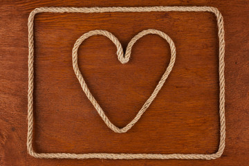 Heart made of rope on a wooden surface