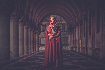 Naklejka premium Woman with a mask wearing red cloak outdoor