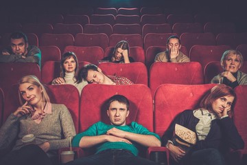 Group of people watching boring movie in cinema - 77153442