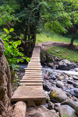 Suspended wooden bridge across mountain river