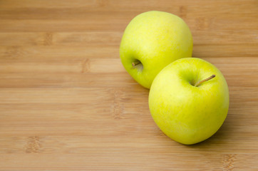two yellow apples on wooden table