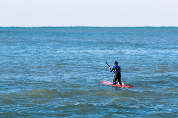 man paddleboarding on red board, surfer