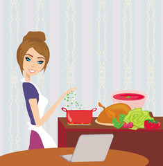 housewife looking in laptop during cooking soup at home kitchen