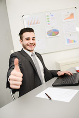 young man in office working with laptop computer and phone