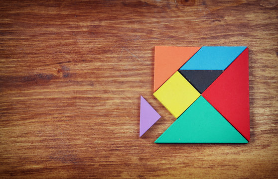 top view of a missing piece in a square tangram puzzle, over woo