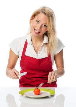 Blonde Frau isst eine Tomate mit Besteck