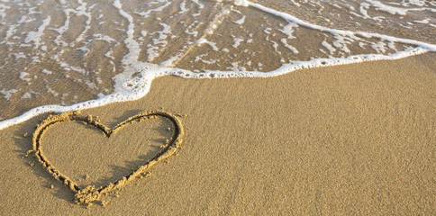 Heart drawn on ocean beach sand.