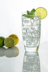 Glass o sparkling water with ice cubes on white background
