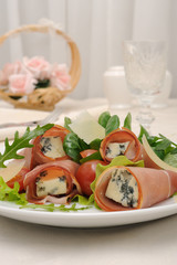 Rolls of jamon with blue cheese in lettuce leaves and parmesan