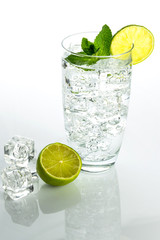 Glass o sparkling water with ice cubes on white background