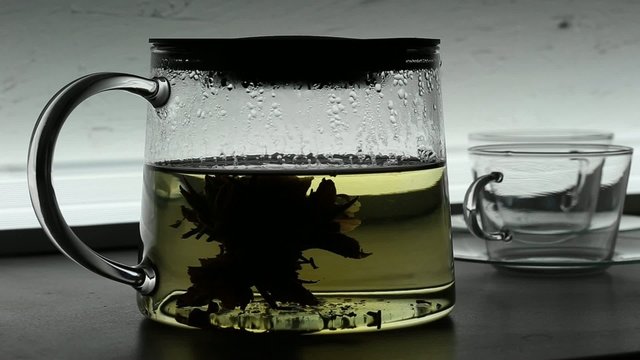 Pouring chinese green tea  into glass teapot
