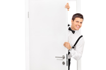 Elegant young guy posing behind a door