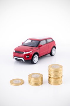 Saving Money To Buy A Vehicle. Coins And Car Toy On White