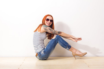 Laughing beautiful woman with sunglasses sitting on the floor