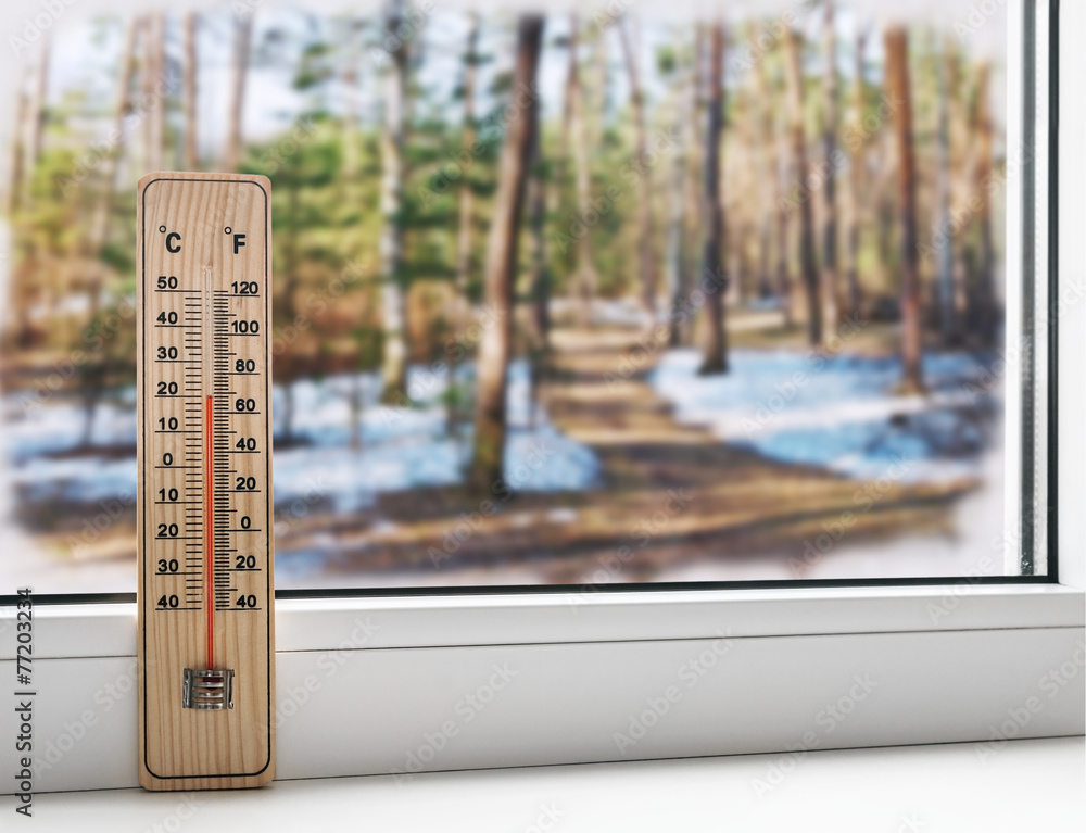 Wall mural thermometer on a frozen window and cold weather in the spring st
