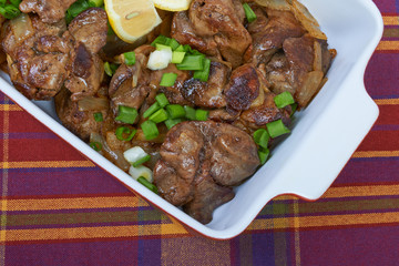 Fried chicken liver in a ceramic plate isolated on a checkered t