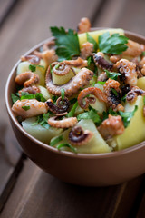 Octopus salad with potato and parsley, close-up, studio shot